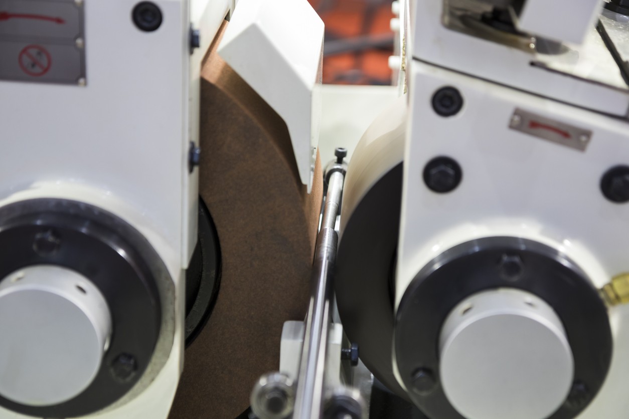 Centerless grinding process showing workpiece positioned between grinding wheel and regulating wheel with support blade.